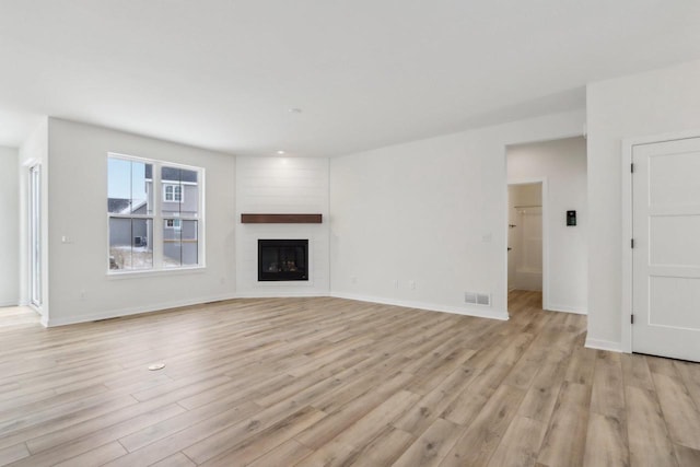 unfurnished living room with a fireplace and light hardwood / wood-style floors