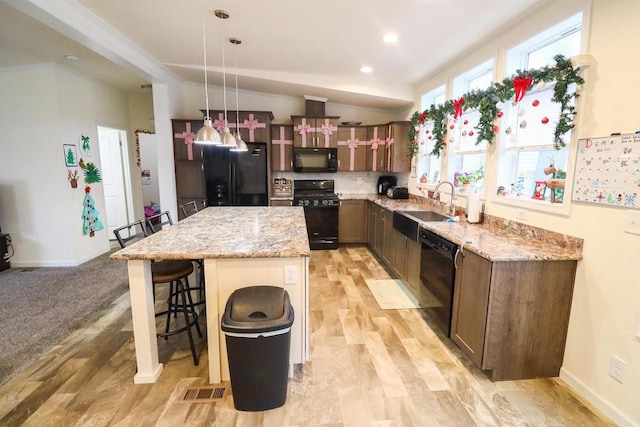 kitchen with pendant lighting, black appliances, light stone countertops, a kitchen island, and a kitchen bar