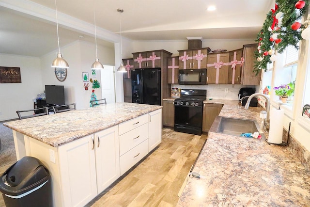 kitchen with white cabinetry, sink, a kitchen bar, a kitchen island, and black appliances