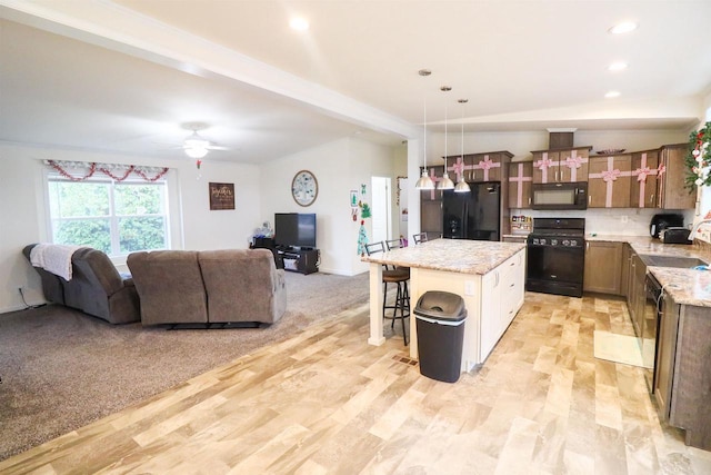 kitchen with ceiling fan, a center island, hanging light fixtures, a breakfast bar, and black appliances