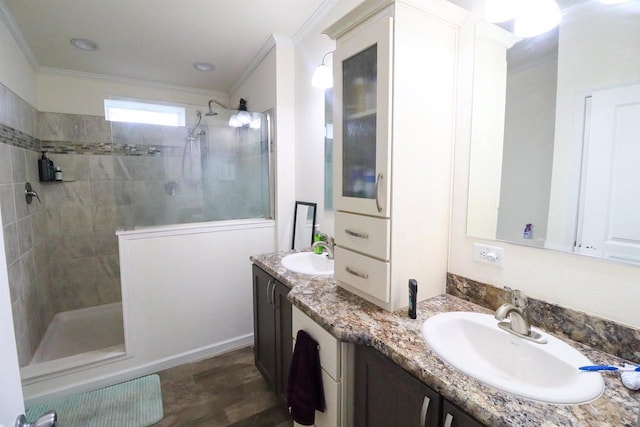 bathroom featuring a tile shower, vanity, wood-type flooring, and ornamental molding