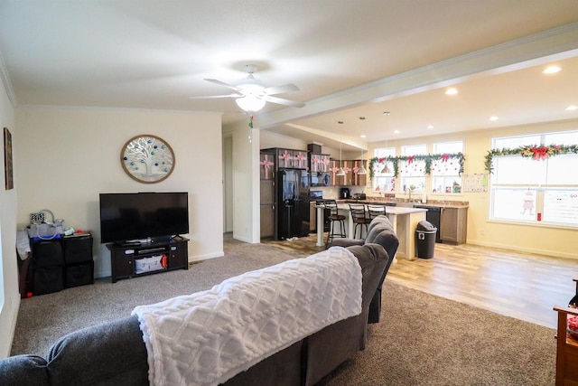 living room with ceiling fan, ornamental molding, and light carpet