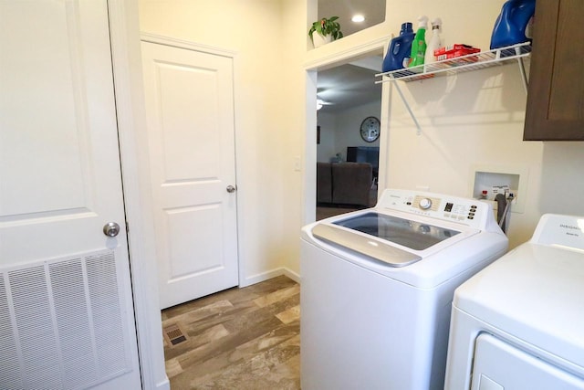 clothes washing area featuring cabinets, independent washer and dryer, and light hardwood / wood-style floors