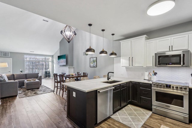 kitchen with decorative light fixtures, white cabinetry, sink, and appliances with stainless steel finishes