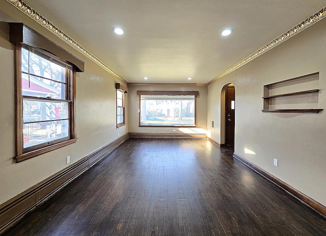 unfurnished living room with a baseboard heating unit, dark wood-type flooring, and crown molding