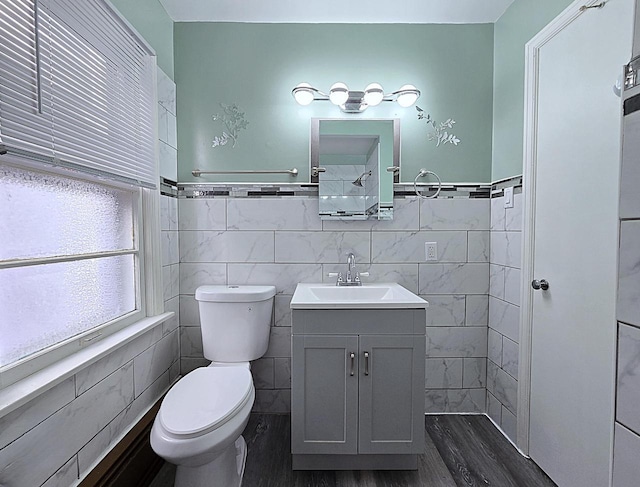 bathroom with wood-type flooring, vanity, toilet, and tile walls