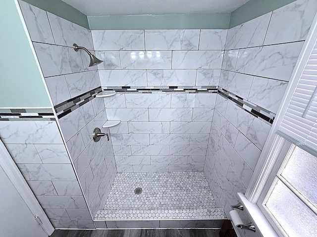 bathroom with hardwood / wood-style floors and a tile shower