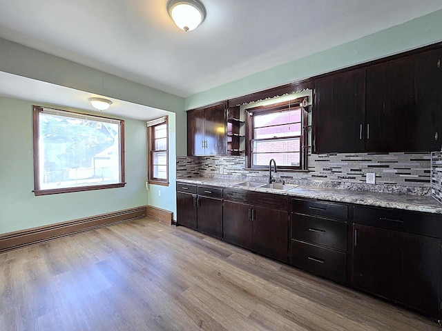 kitchen featuring sink, light hardwood / wood-style flooring, a wealth of natural light, a baseboard radiator, and dark brown cabinetry