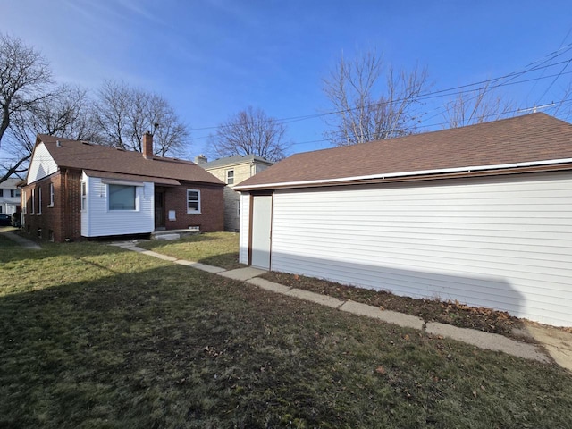 back of property featuring an outbuilding, a garage, and a lawn