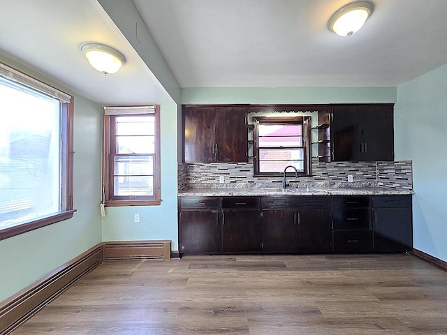 kitchen featuring tasteful backsplash, dark brown cabinetry, sink, and light hardwood / wood-style flooring