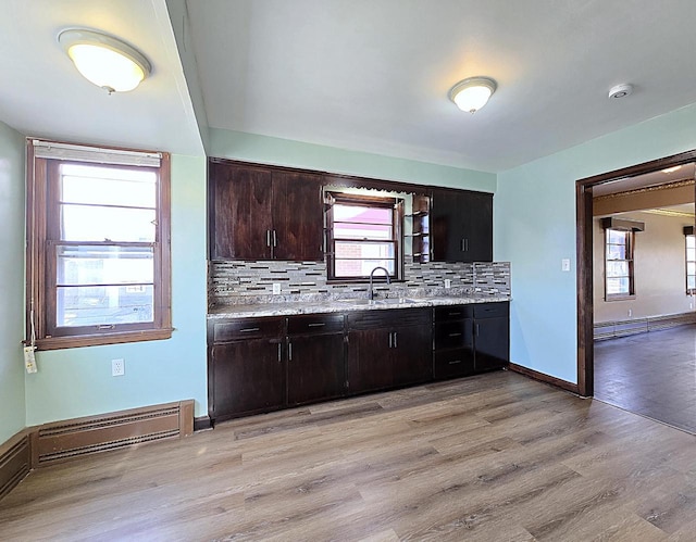 kitchen with sink, a baseboard radiator, tasteful backsplash, light hardwood / wood-style flooring, and dark brown cabinets