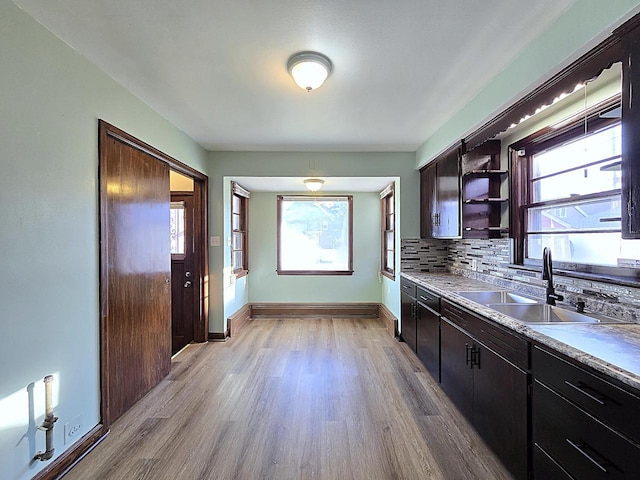 kitchen featuring decorative backsplash, light hardwood / wood-style flooring, baseboard heating, and sink