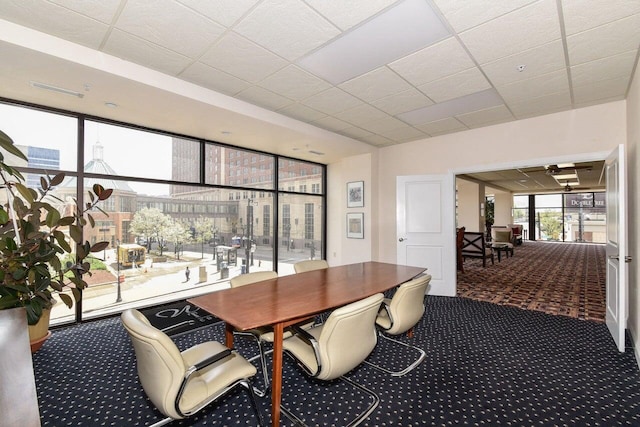 carpeted dining space featuring a drop ceiling