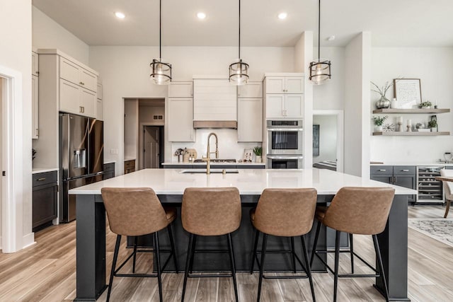 kitchen featuring sink, decorative light fixtures, light wood-type flooring, a large island, and stainless steel appliances