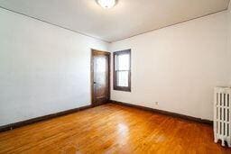 unfurnished room featuring dark wood-type flooring and radiator