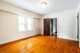 empty room with hardwood / wood-style floors and radiator heating unit