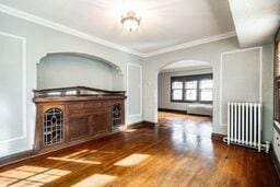 interior space with dark hardwood / wood-style flooring, radiator heating unit, and crown molding