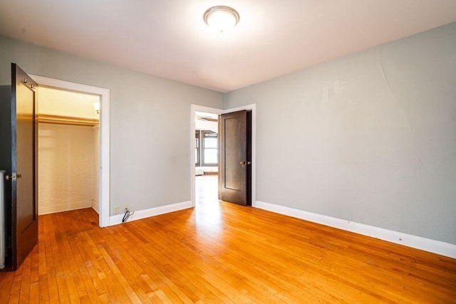 unfurnished bedroom featuring a walk in closet, a closet, and hardwood / wood-style flooring