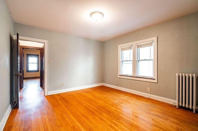 empty room featuring radiator heating unit and light hardwood / wood-style floors