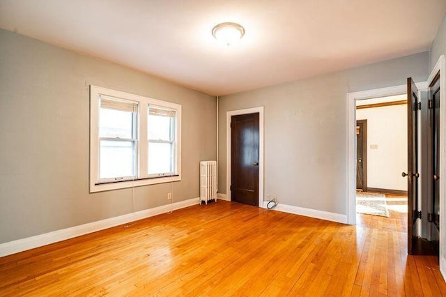 unfurnished room with radiator and hardwood / wood-style floors