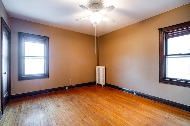 spare room featuring radiator, ceiling fan, and hardwood / wood-style flooring