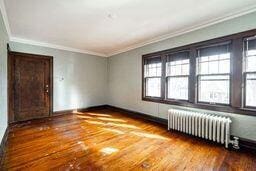 spare room featuring hardwood / wood-style floors, ornamental molding, and radiator