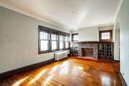 unfurnished living room with radiator heating unit, dark hardwood / wood-style floors, plenty of natural light, and crown molding