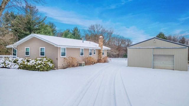 view of snowy exterior featuring central air condition unit, an outdoor structure, and a garage