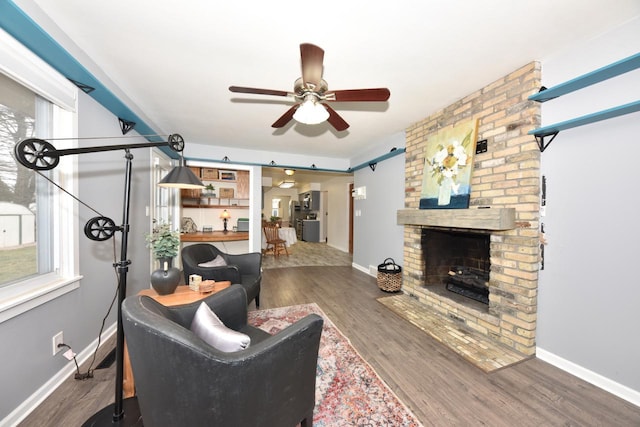 living room with ceiling fan, a fireplace, and dark wood-type flooring