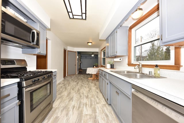 kitchen with sink, stainless steel appliances, and light hardwood / wood-style flooring