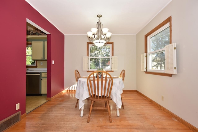 dining room with ornamental molding, light hardwood / wood-style floors, and a notable chandelier