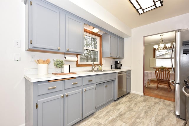 kitchen featuring sink, gray cabinets, appliances with stainless steel finishes, decorative light fixtures, and a chandelier