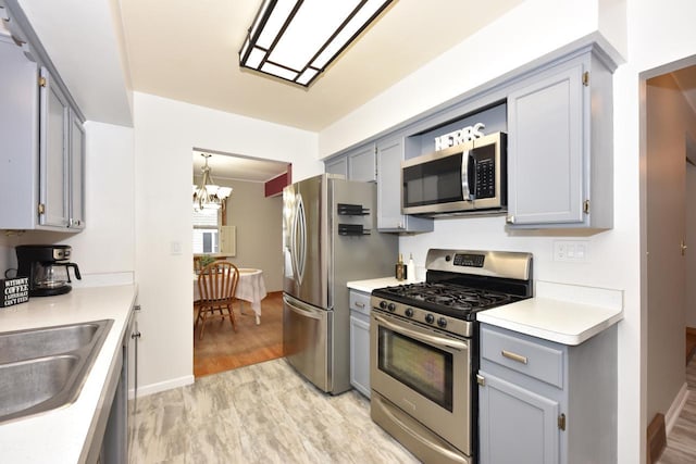 kitchen featuring an inviting chandelier, sink, hanging light fixtures, light wood-type flooring, and appliances with stainless steel finishes