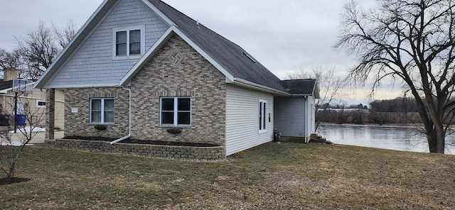 view of home's exterior featuring a water view and a lawn