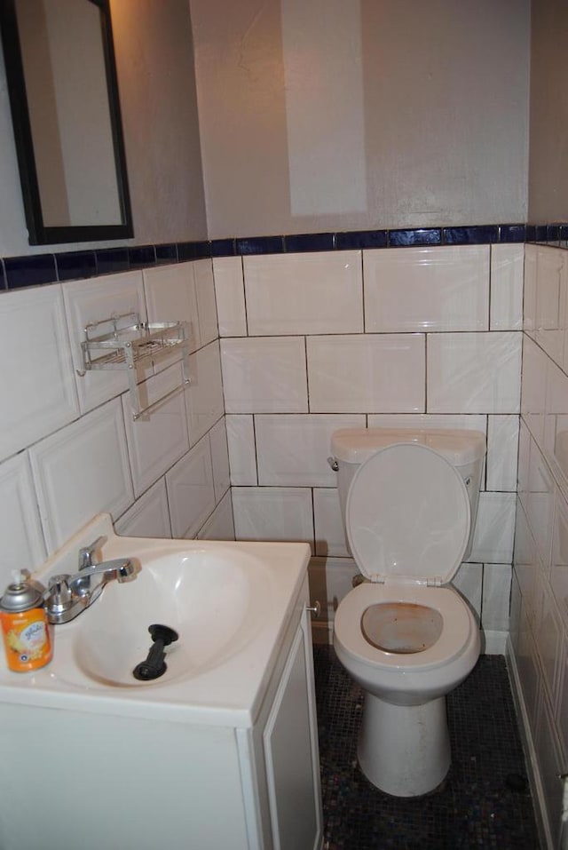 bathroom featuring tile patterned floors, vanity, tile walls, and toilet