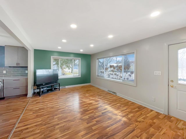 unfurnished living room featuring plenty of natural light and light wood-type flooring