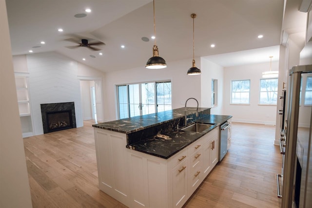 kitchen with dishwasher, dark stone counters, sink, decorative light fixtures, and white cabinetry