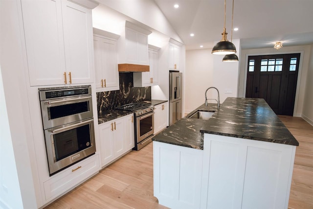 kitchen with white cabinetry, sink, an island with sink, decorative light fixtures, and appliances with stainless steel finishes