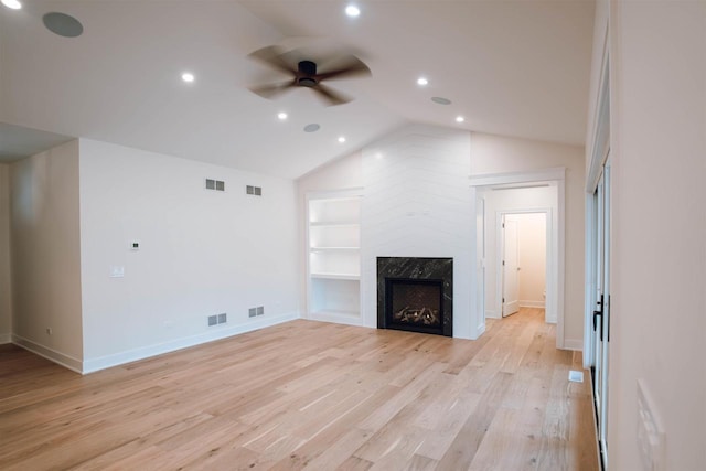 unfurnished living room with light wood-type flooring, vaulted ceiling, ceiling fan, built in features, and a fireplace