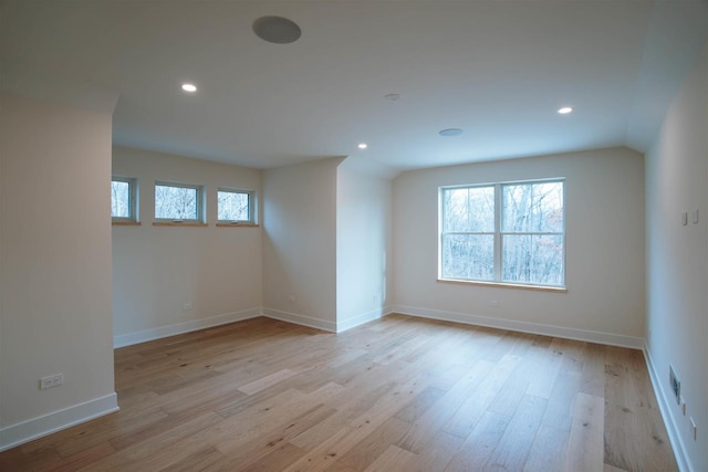 spare room featuring light hardwood / wood-style floors and lofted ceiling