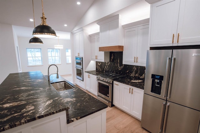 kitchen featuring vaulted ceiling, sink, pendant lighting, high quality appliances, and white cabinets