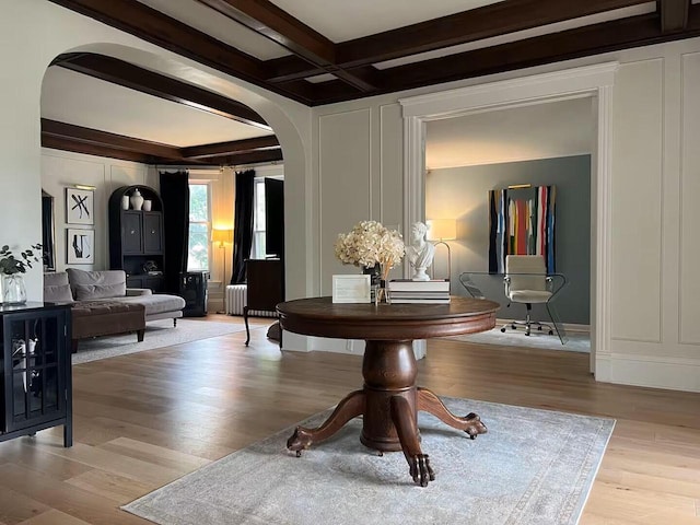 sitting room with beam ceiling, light wood-type flooring, radiator heating unit, and coffered ceiling