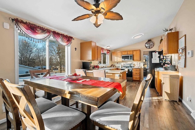 dining room with dark hardwood / wood-style floors, ceiling fan, sink, and vaulted ceiling