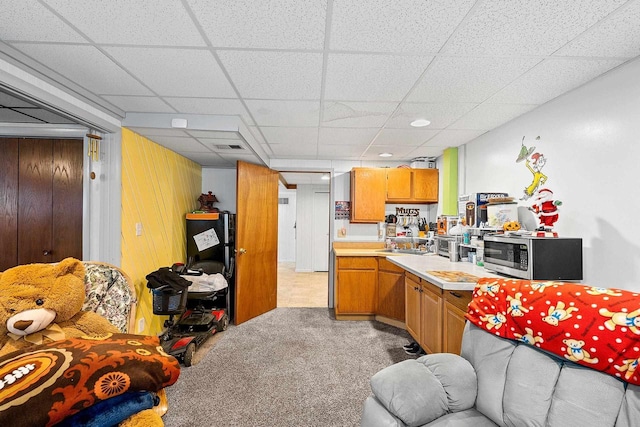 kitchen featuring light carpet, a drop ceiling, and wooden walls