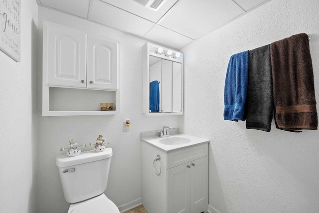 bathroom with a drop ceiling, vanity, and toilet