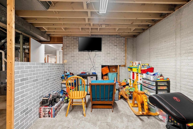 game room with carpet and brick wall