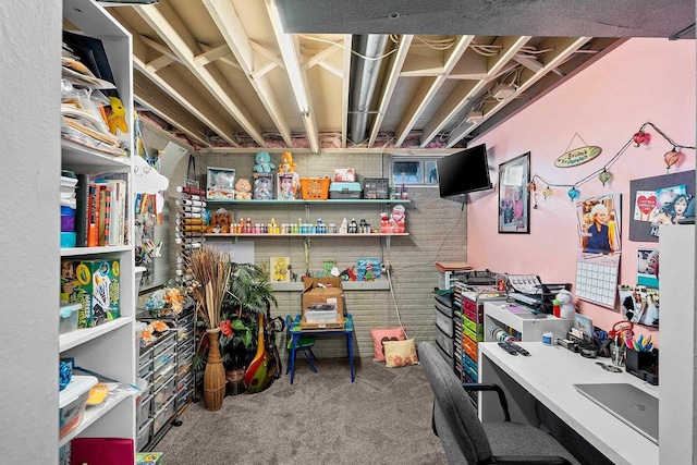 carpeted home office featuring brick wall