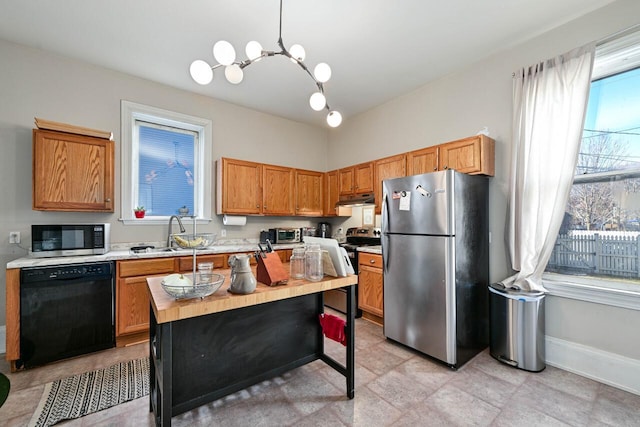 kitchen with decorative light fixtures, sink, stainless steel appliances, and a wealth of natural light