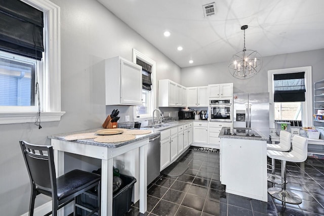 kitchen featuring a kitchen island, decorative light fixtures, a breakfast bar, white cabinets, and appliances with stainless steel finishes