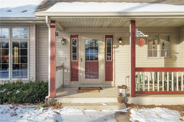 snow covered property entrance featuring covered porch